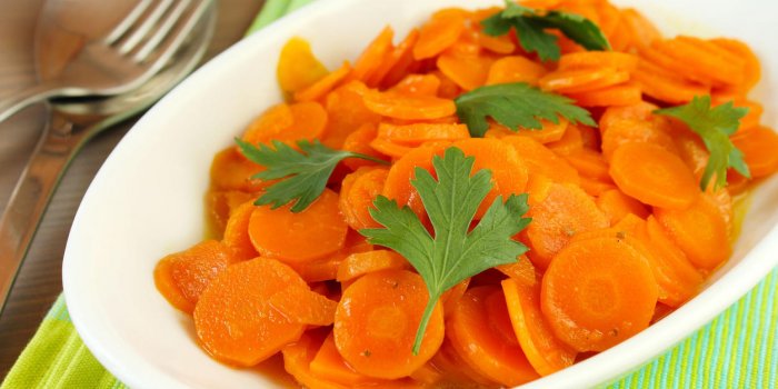 carottes tranchÃ©es cuites avec des feuilles de persil frais servi sur une plaque ovale blanche