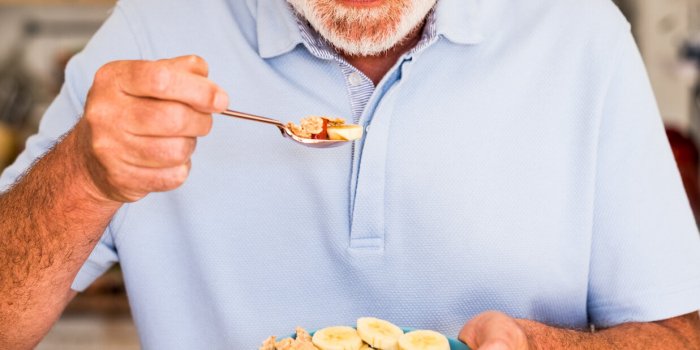 smiling elderly man holding a bowl of fresh and dried fruits breakfast or lunch time, healthy eating