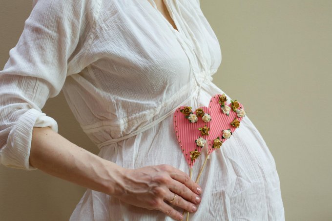 two pink hearts in the hand of a pregnant woman