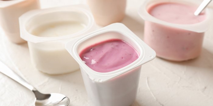 composition with plastic cups with yogurt on white table