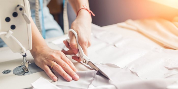 pattern, scissors, tape measure, and a sewing machine workplace of seamstress dressmaker cuts dress detail on the sketch ...