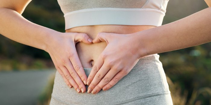 shot of a fit young woman forming a heart shape over her stomach