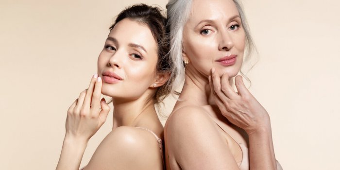 elderly and young women with smooth skin and natural makeup standing back-to-back thinking, planning, dreaming