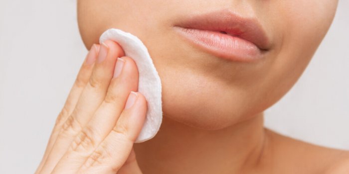 cropped shot of a young caucasian woman cleaning her face with cotton pad on a white background skin care, cosmetology ev...