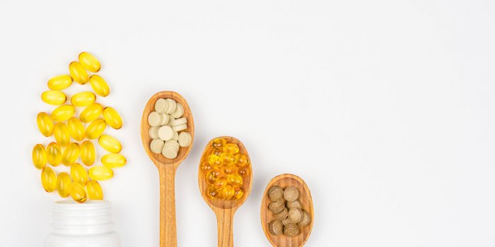 dietary supplements and vitamin pills in bottle and spoons on white background health care concept