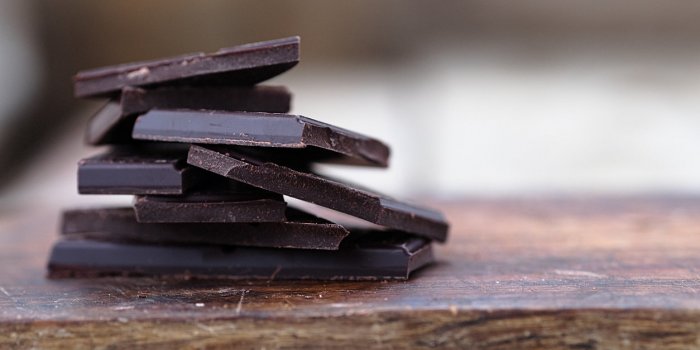 stack of broken dark chocolate bar pieces on a wooden background horizontal