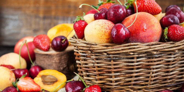 fresh ripe summer berries and fruits (peaches, apricots, cherry and strawberry) in wicker basket