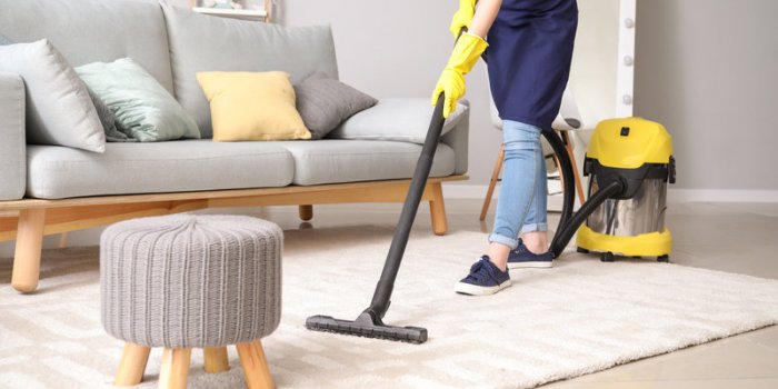 female janitor with vacuum cleaner in room