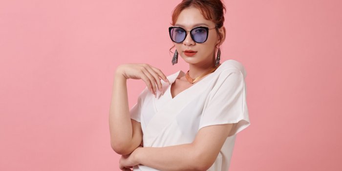 studio portrait of fashionable transgender woman in white blouse and sunglasses
