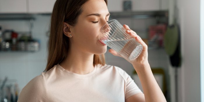 thirsty young woman drinking fresh water from glass home office kitchen interior headshot portrait dehydration prevention...