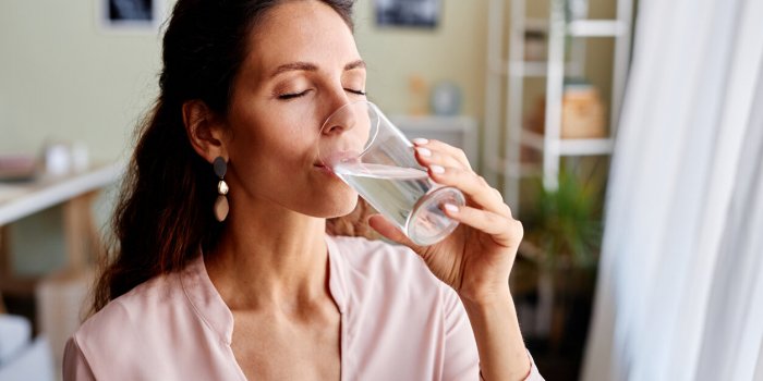 portrait of beautiful adult woman drinking water in morning while starting day at home