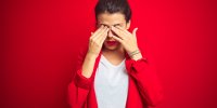 young beautiful business woman standing over red isolated background rubbing eyes for fatigue and headache, sleepy and ti...