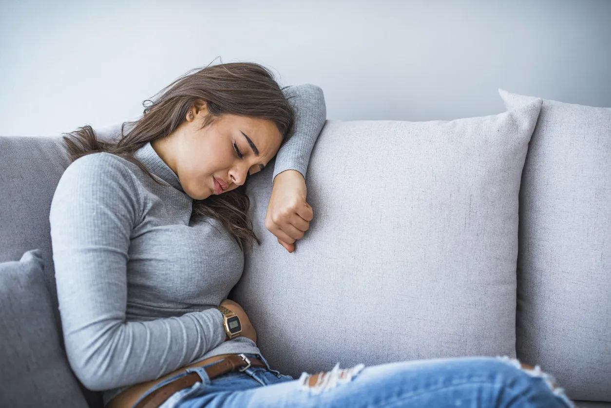 young woman sitting on the bed with pain woman stomachache, feel pain for period concept woman lying on sofa looking sick in the living room horizontal view of woman in bed having menstruation