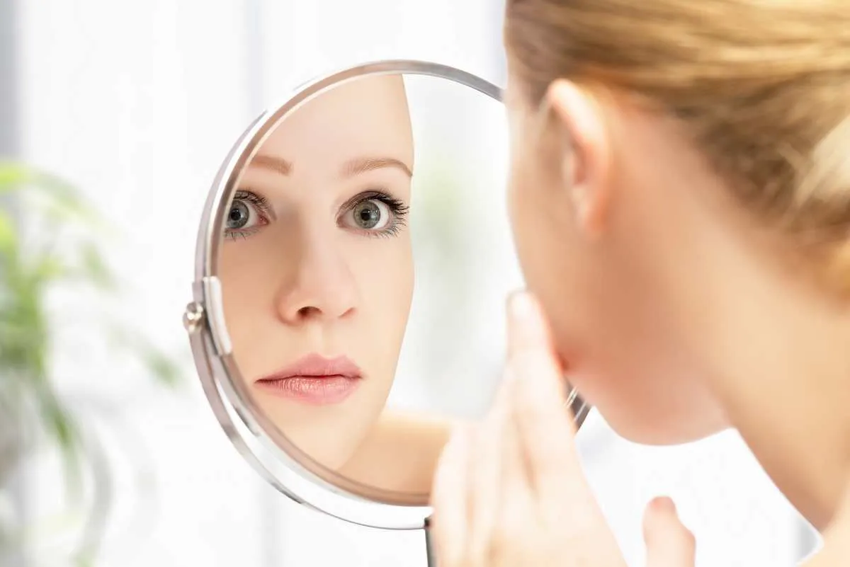 face of young beautiful healthy woman and reflection in the mirror