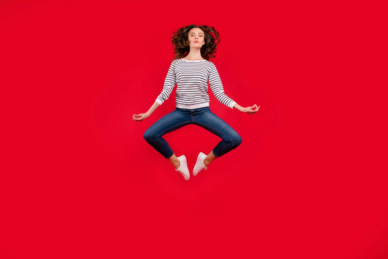 full length size body photo of fly high pretty charming she her girl getting yoga energy in lotus pose wearing striped white casual sweater on red vivid bright background