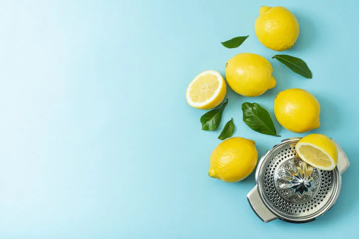 ripe lemons flat lay with leaves on blue backgroundwith one citrus juicer copy space, top view ripe lemons flat lay with leaves on blue backgroundwith one citrus juicer copy space, top view