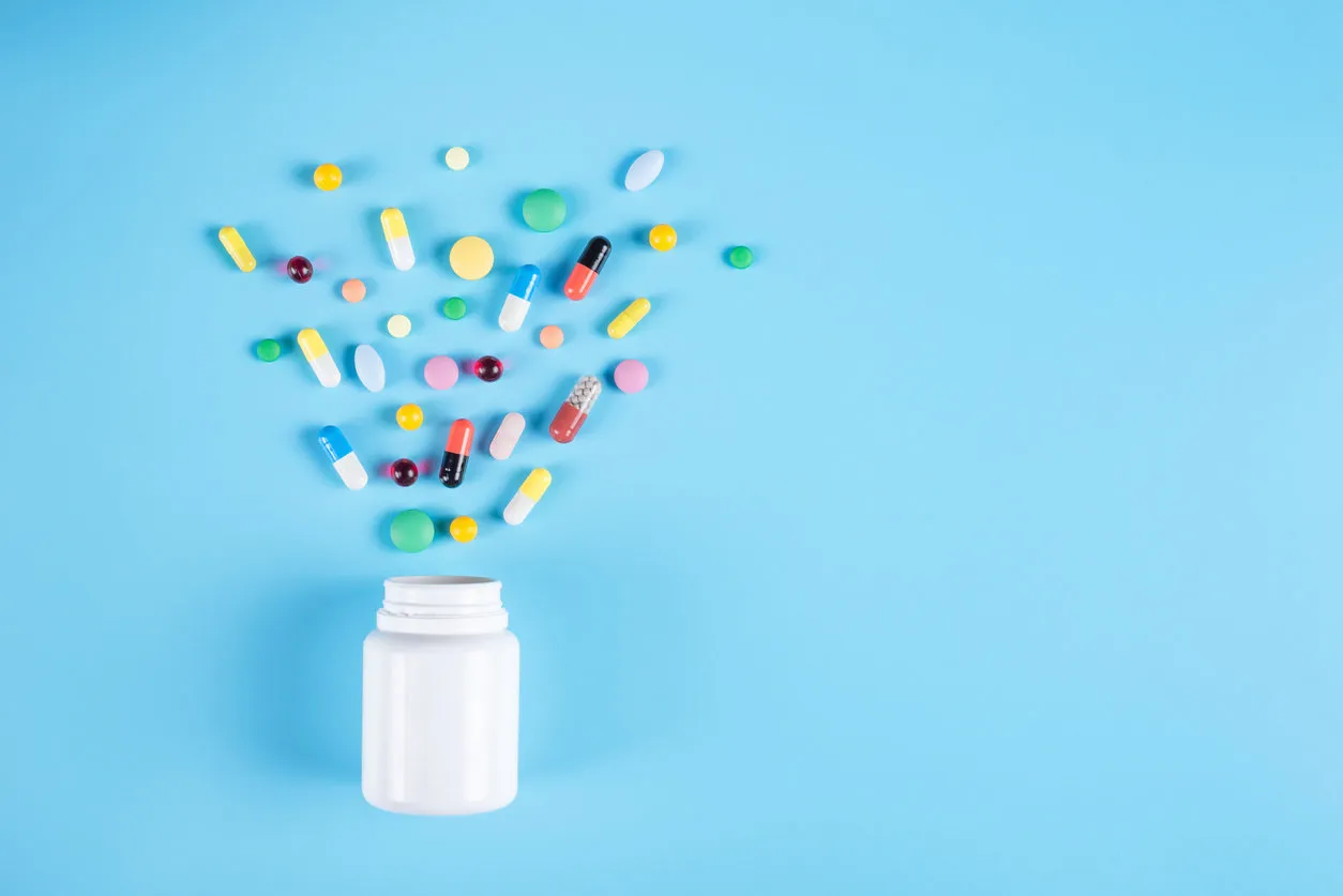 assorted pharmaceutical medicine pills, tablets and white bottle on blue background copy space for text assorted pharmaceutical medicine pills, tablets and white bottle on blue background copy space for text