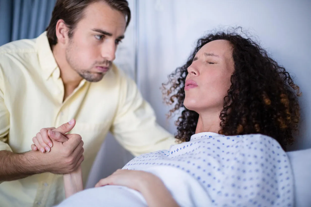 man comforting pregnant woman during labor in ward of hospital