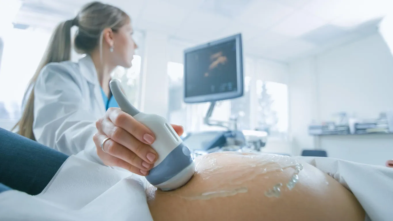 in the hospital, close-up shot of the doctor does ultrasound sonogram procedure to a pregnant woman obstetrician moving transducer on the belly of the future mother in the hospital, close-up shot of the doctor does ultrasound sonogram procedure to a pregnant woman obstetrician moving transducer on the belly of the future mother