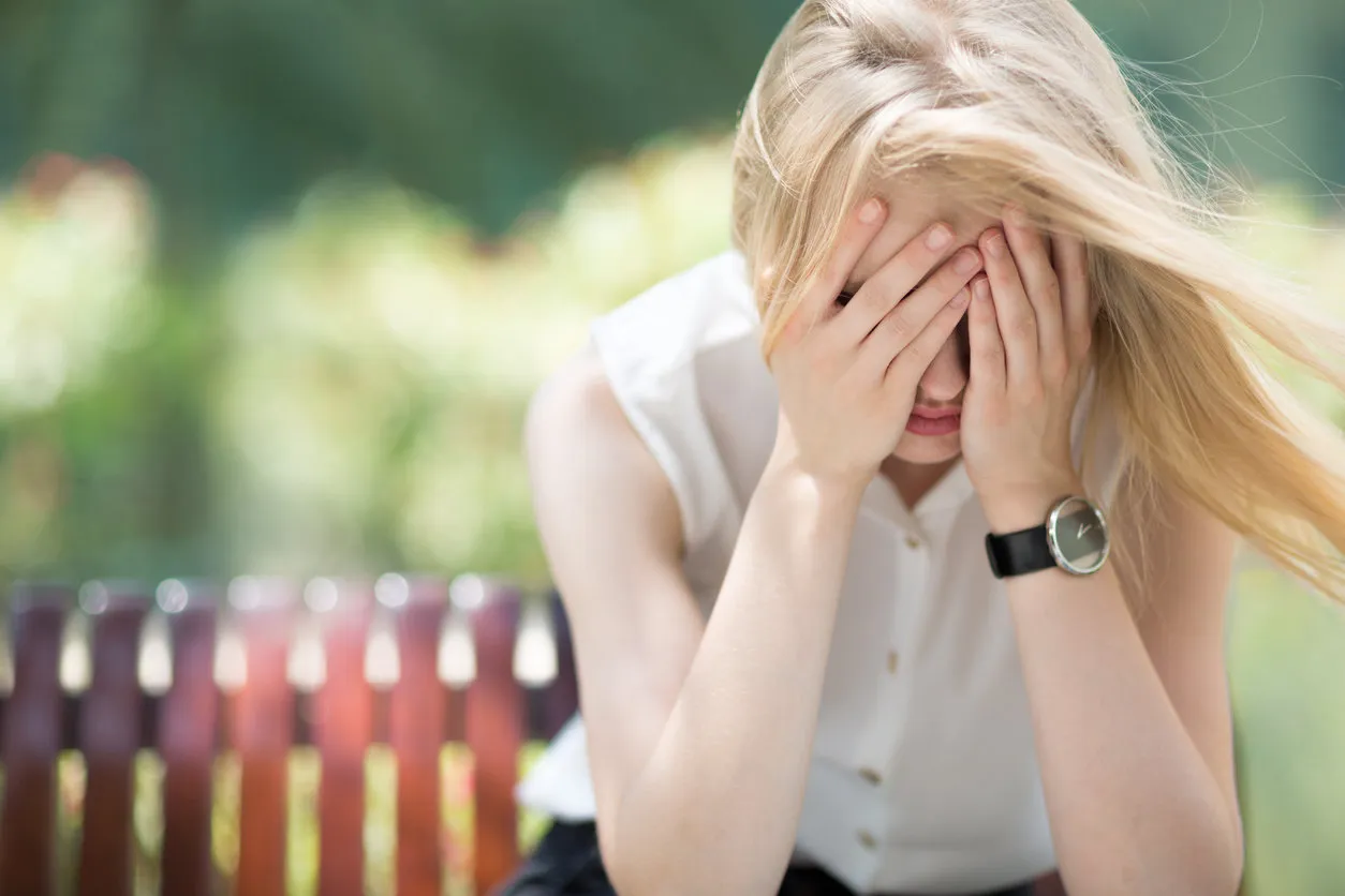 portrait of young woman covering her face with both hands in defeat and frustration portrait of young woman covering her face with both hands in defeat and frustration