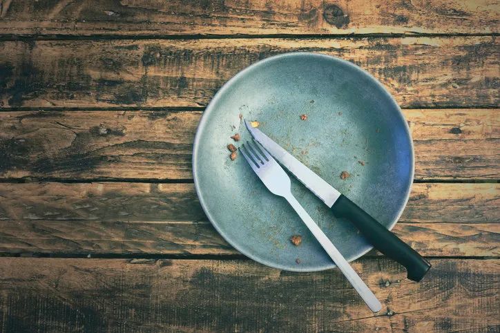 a dirty plate after having eaten the dish on a grungy wooden table top view a dirty plate after having eaten the dish on a grungy wooden table top view