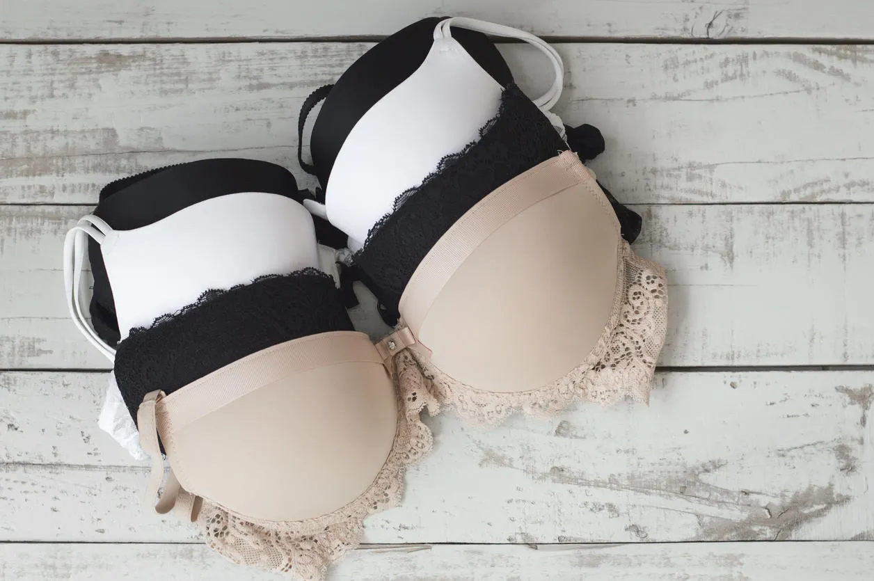 many women's bra of beige, white and black colors on gray wooden background underwear fashion basic lingerie classic bra many women's bra of beige, white and black colors on gray wooden background underwear fashion basic lingerie classic bra