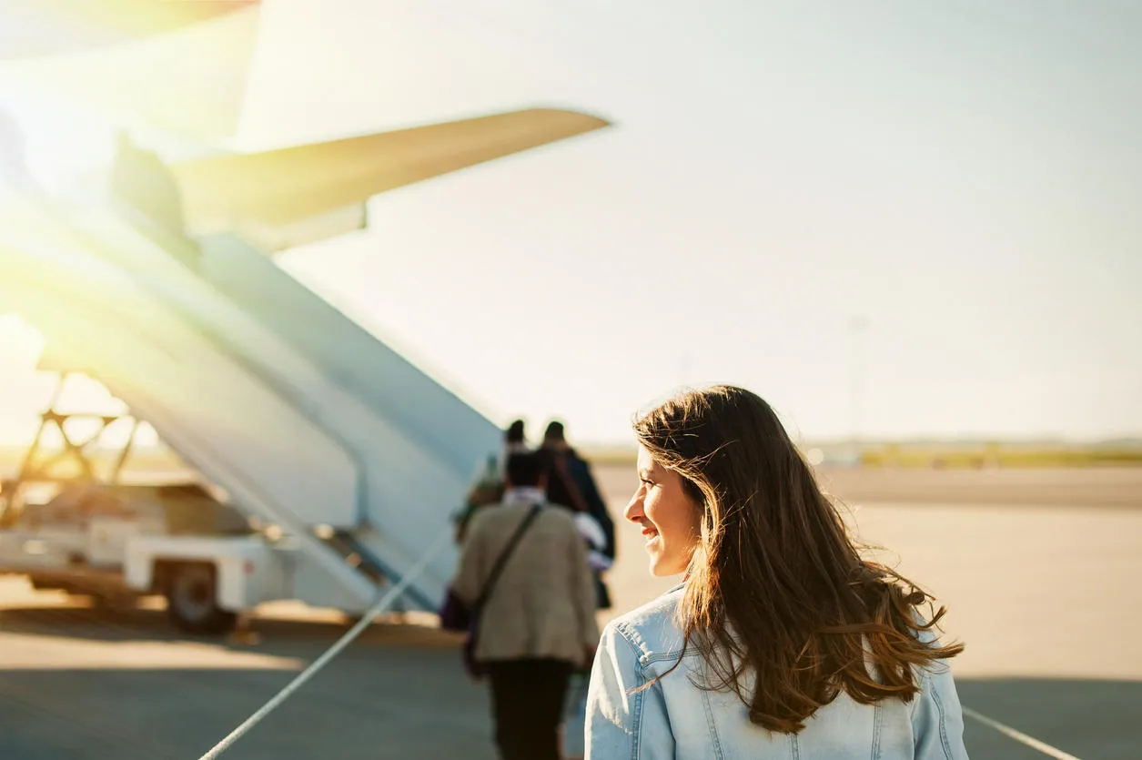 woman tourist passenger getting in to airplane at airport, walking from the terminal to the plane woman tourist passenger getting in to airplane at airport, walking from the terminal to the plane
