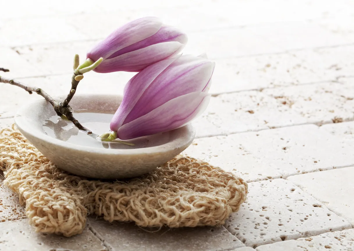 magnolia flowers in stone cup of water for soft exfoliation with loofah glove