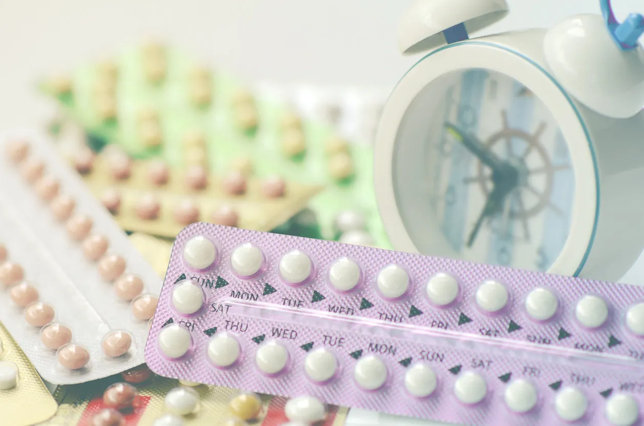 oral contraceptive pills with alarm clock background in time reminder for taking pills