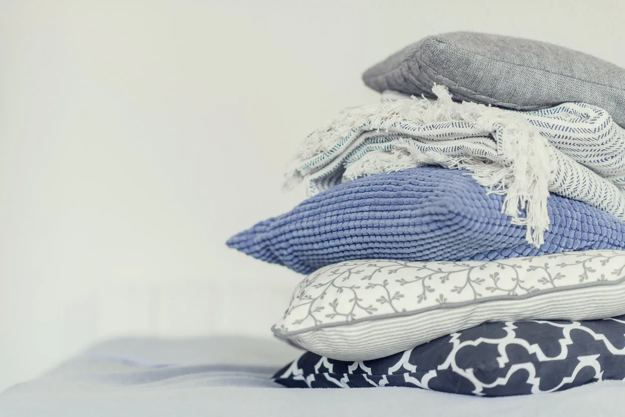 pile of pillows on the edge of the bed, in gray, monochrome