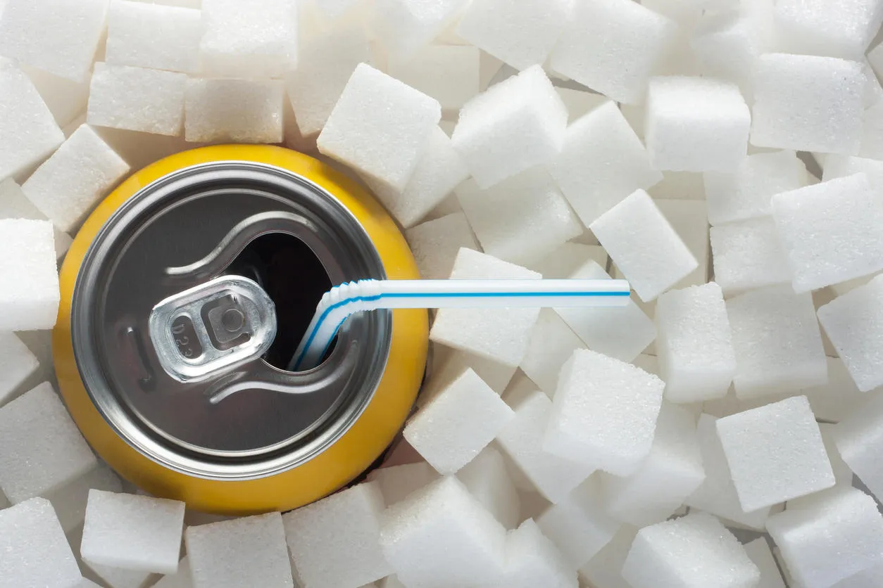unhealthy food concept - sugar in carbonated drink sugar cubes as background and canned drink unhealthy food concept - sugar in carbonated drink sugar cubes as background and canned drink