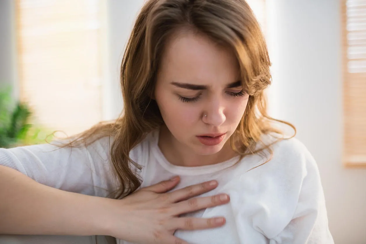 pretty woman suffering from chest pain on couch