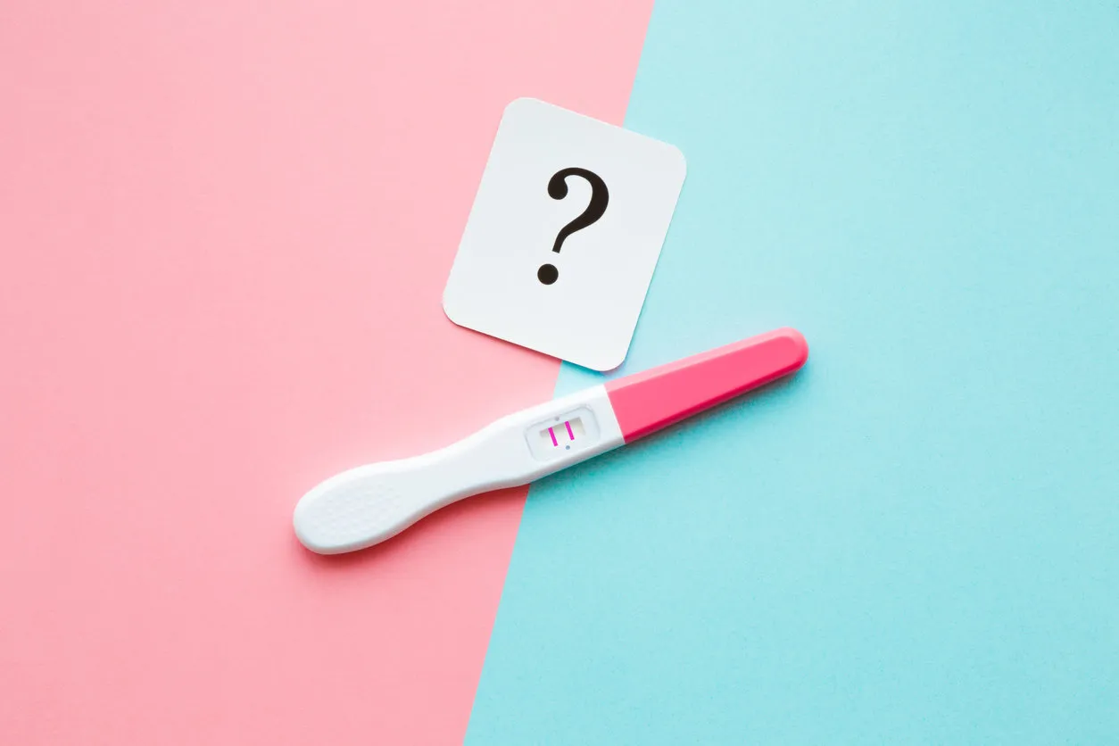 pregnancy test with two stripes and white card of black question mark pastel blue and pink background positive result guessing unborn baby gender closeup pregnancy test with two stripes and white card of black question mark pastel blue and pink background positive result guessing unborn baby gender closeup