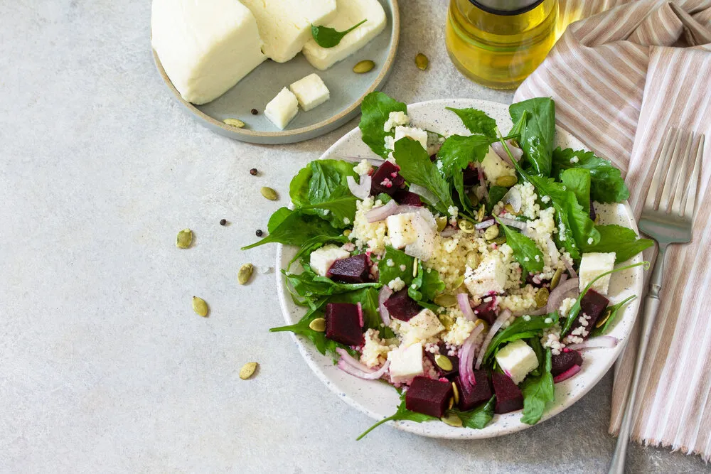 healthy salad with couscous, soft cheese, beetroot and vinaigrette dressing copy space