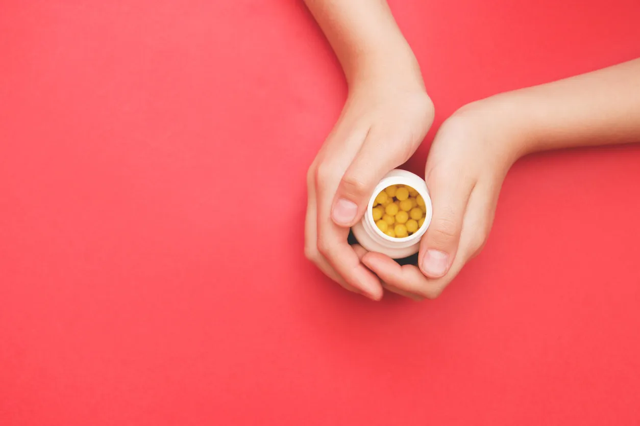 bottle in female hand with yellow pills on red background, selective focus concept for prevention of colds, antidepressants, vitamin , pharmacy bottle in female hand with yellow pills on red background, selective focus concept for prevention of colds, antidepressants, vitamin , pharmacy