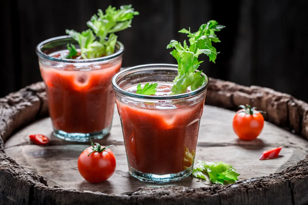 bloody mary cocktail with tomatoes and celery on old barrel