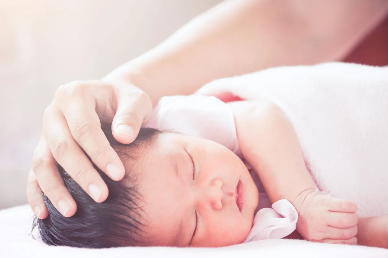 mother hand touching asian newborn baby girl head while she sleeping with tenderness in vintage color tone mother hand touching asian newborn baby girl head while she sleeping with tenderness in vintage color tone