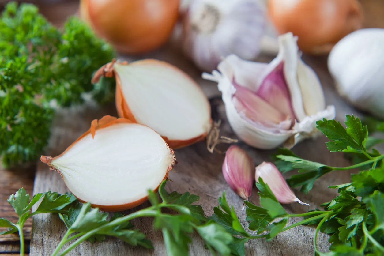 garlic cloves, shallots and white onions  - food ingredient on wooden board, decorated with fresh parsley