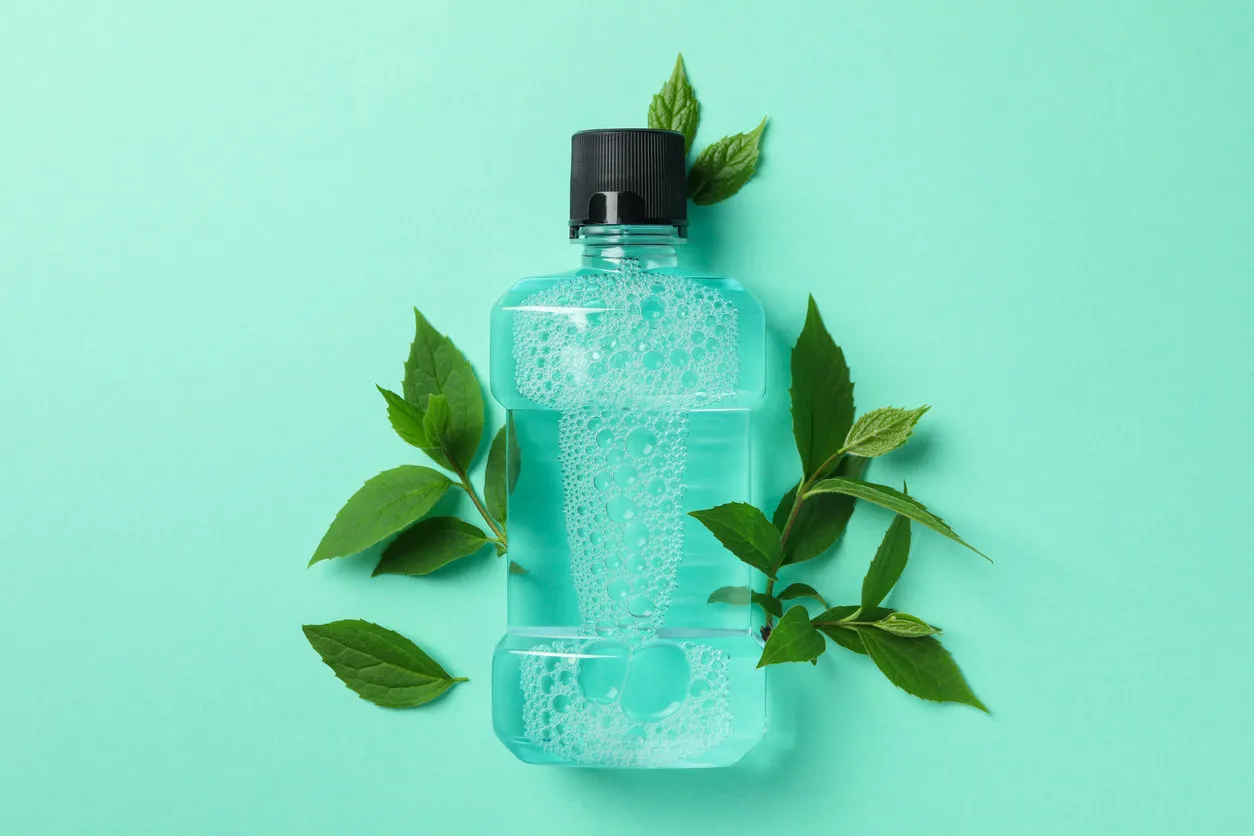 mouthwash and leaves on mint background, space for text
