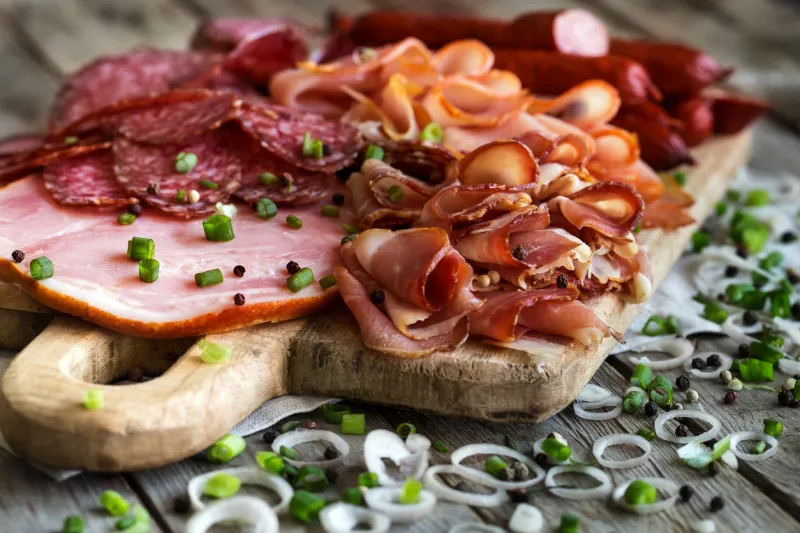 mix of meat appetizers - salami, ham, smoked turkey, sausages and prosciutto - on rustic wooden background mix of meat appetizers - salami, ham, smoked turkey, sausages and prosciutto - on rustic wooden background