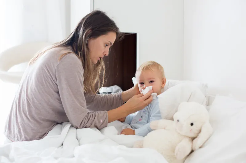 mother and baby in pajamas, early in the morning, mom taking care of her sick toddler boy baby in bed with fever and running nose mother and baby in pajamas, early in the morning, mom taking care of her sick toddler boy baby in bed with fever and running nose
