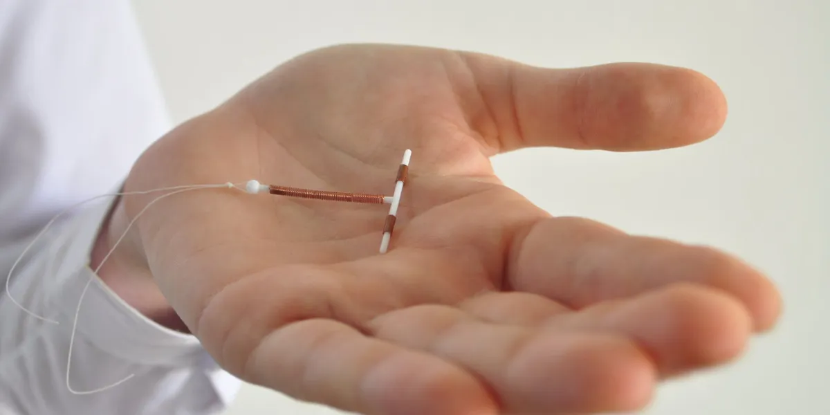 holding an iud birth control copper coil device in hand, used for contraception - side view holding an iud birth control copper coil device in hand, used for contraception - side view