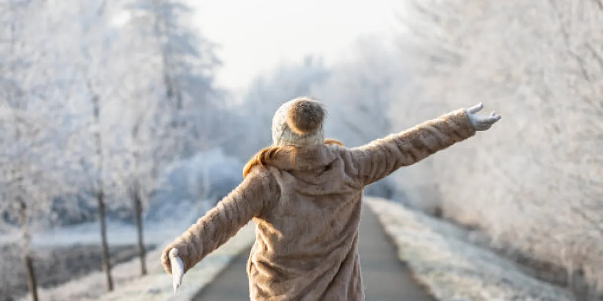 fashion model wearing fur coat and knitted hat with arms outstretched outdoors cold weather with frozen trees fashion model wearing fur coat and knitted hat with arms outstretched outdoors cold weather with frozen trees