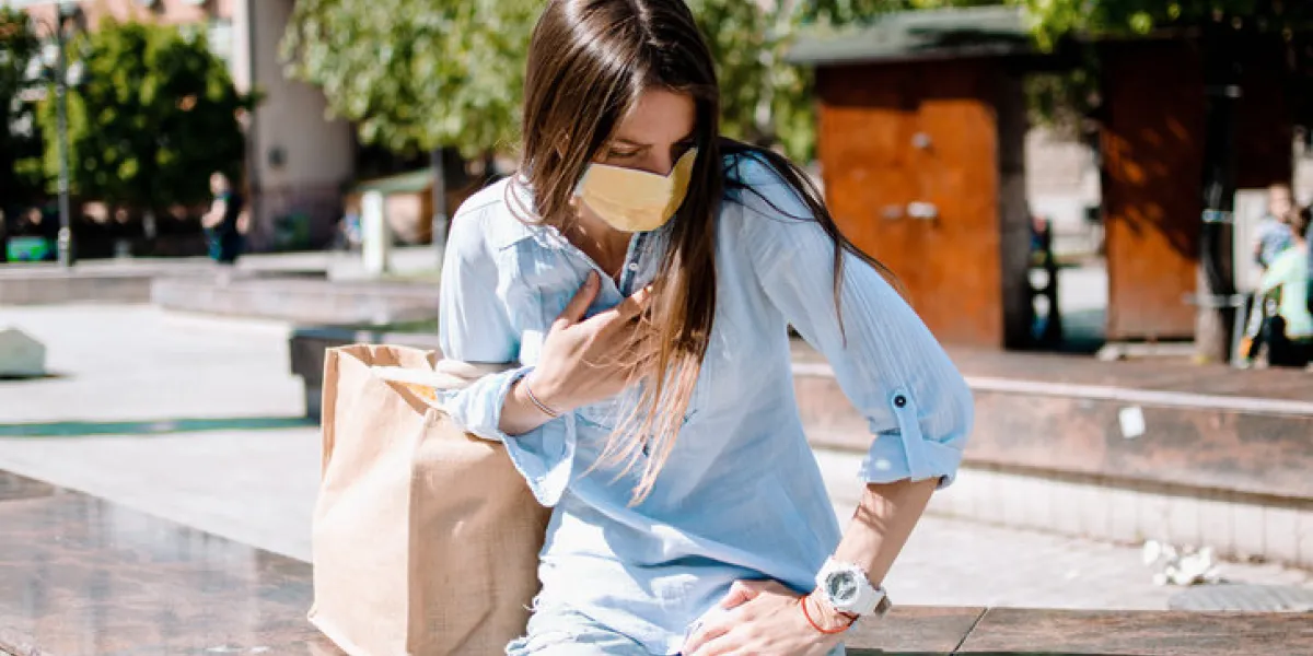 asthmatic female with respiratory problem resting in the city street woman with madical protective mask out of breath,holding hand on chest asthmatic female with respiratory problem resting in the city street woman with madical protective mask out of breath,holding hand on chest