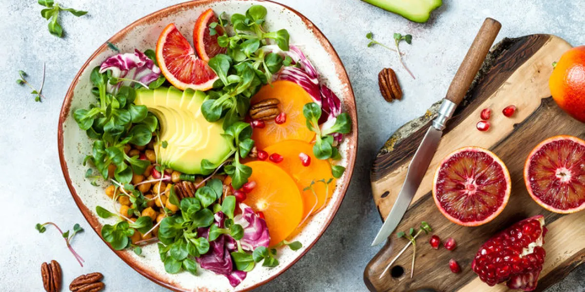 vegan, detox buddha bowl with turmeric roasted chickpeas, greens, avocado, persimmon, blood orange, nuts and pomegranate top view, flat lay vegan, detox buddha bowl with turmeric roasted chickpeas, greens, avocado, persimmon, blood orange, nuts and pomegranate top view, flat lay
