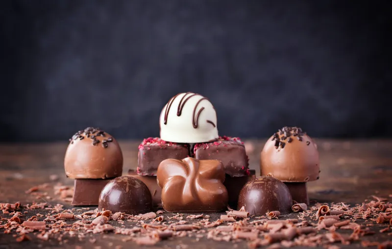 traditional belgian chocolate variety over rustic wooden board, decorated with chocolate swirls traditional belgian chocolate variety over rustic wooden board, decorated with chocolate swirls