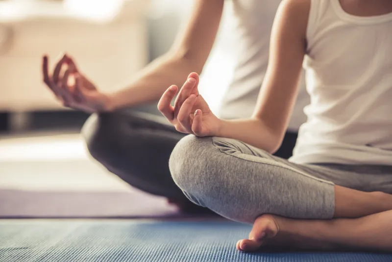 cropped image of young woman and her little daughter doing yoga together at home cropped image of young woman and her little daughter doing yoga together at home