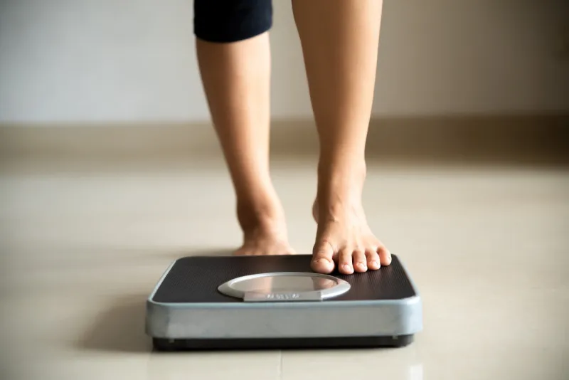 female leg stepping on weigh scales healthy lifestyle, food and sport concept female leg stepping on weigh scales healthy lifestyle, food and sport concept