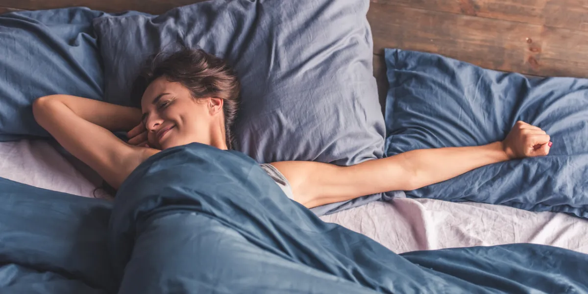 beautiful young woman is stretching and smiling while lying in bed in the morning beautiful young woman is stretching and smiling while lying in bed in the morning