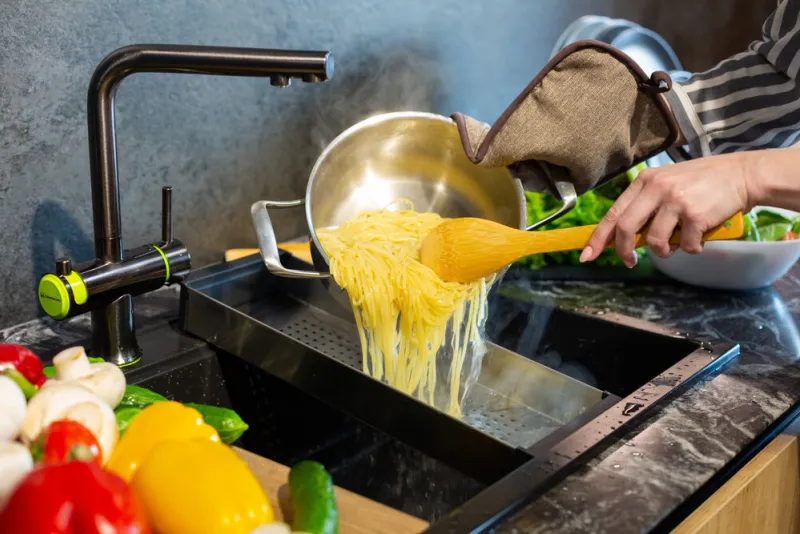close-up a woman in an apron cooks spaghetti in the kitchen close-up a woman in an apron cooks spaghetti in the kitchen